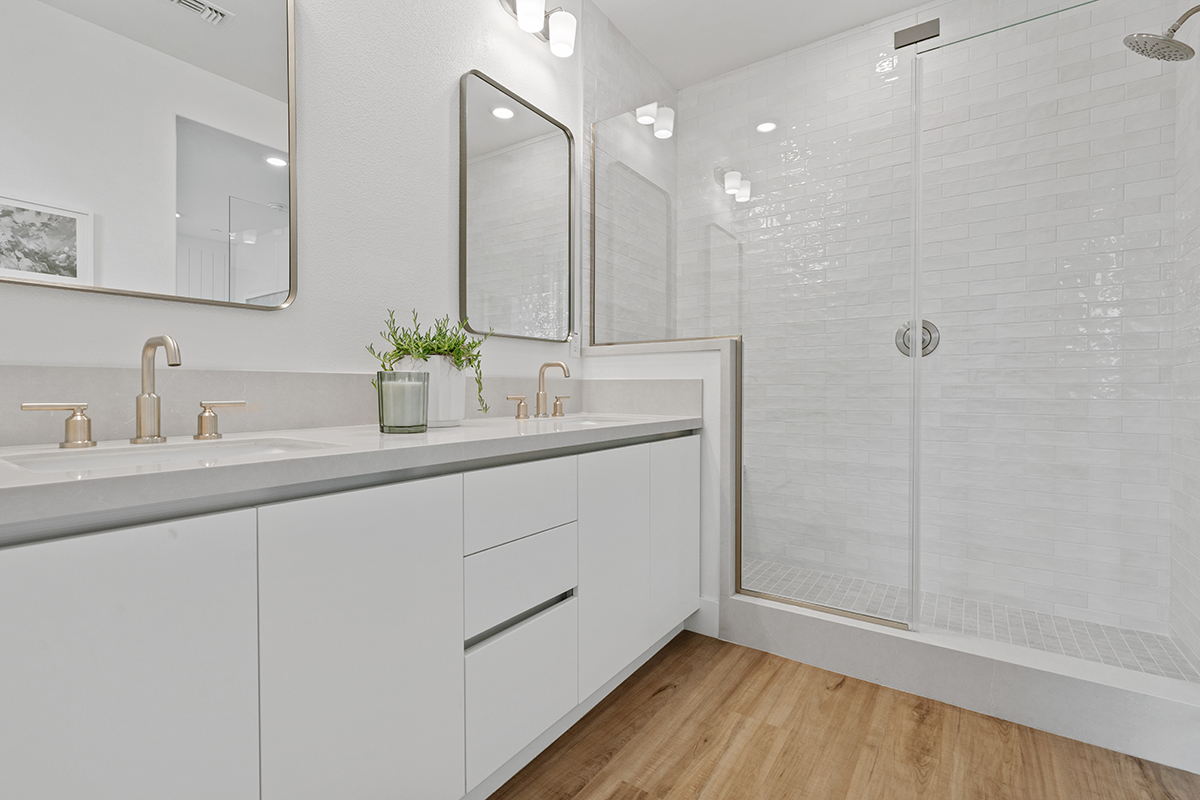 Walk-in shower with tile surround and frameless glass enclosure at primary bath